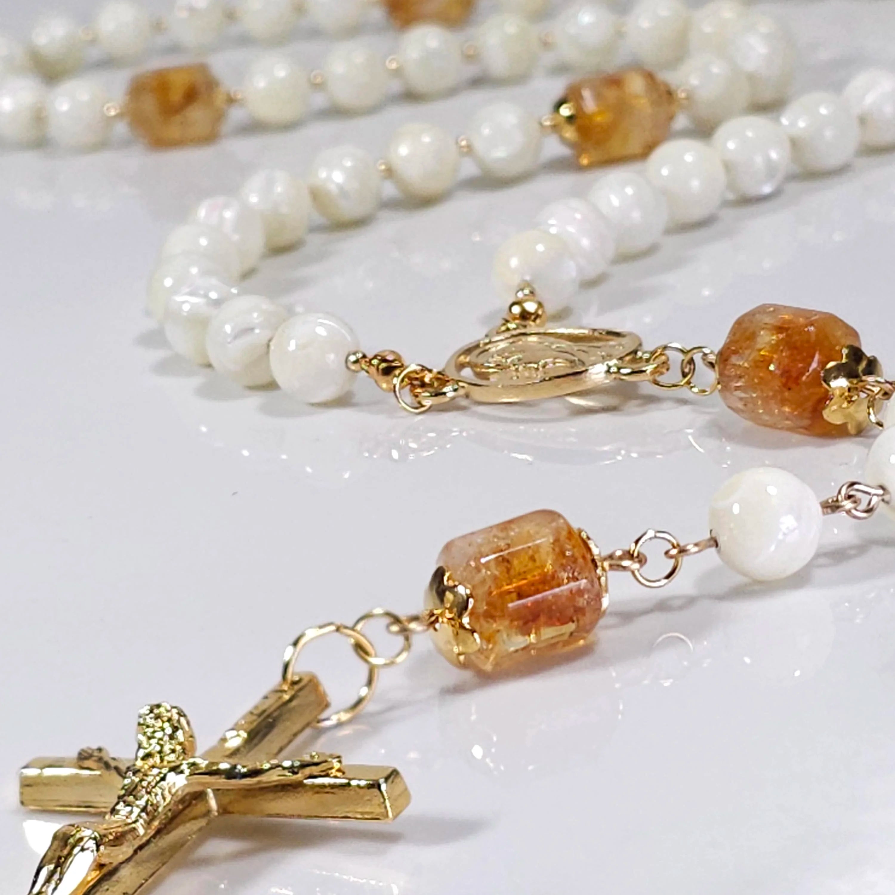 Star of the sea rosary laying on white marble.