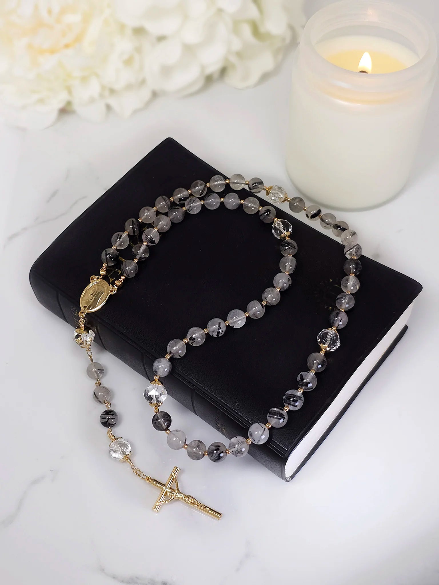 Unique rosary showcasing a blend of intricate Quartz and Tourmaline beads, laying gracefully.