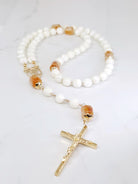 Rosary necklace combining White Mother of Pearl and sunlit Citrine, adorned with a Madonna medal, laid on a white table.