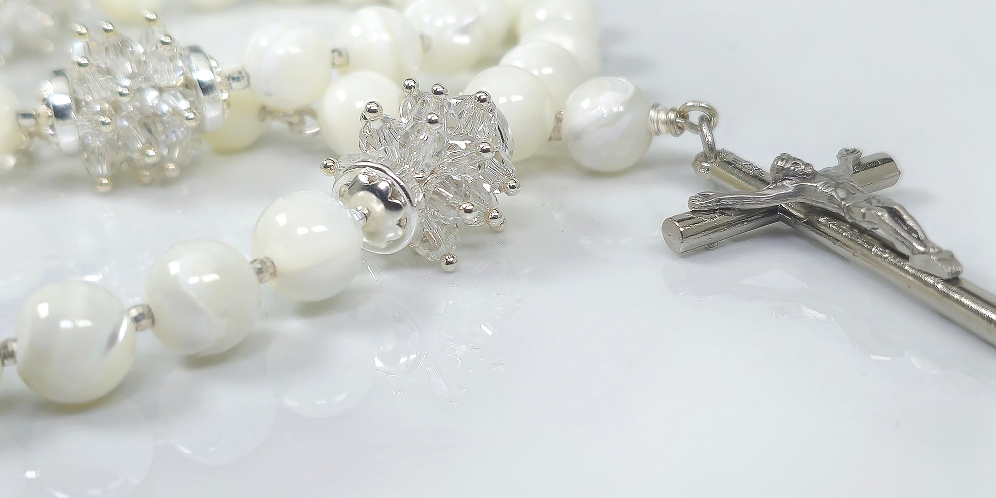 White Mother of Pearl Rosary adorned with silver white Swarovski crystal and sterling silver findings on top of a white top.