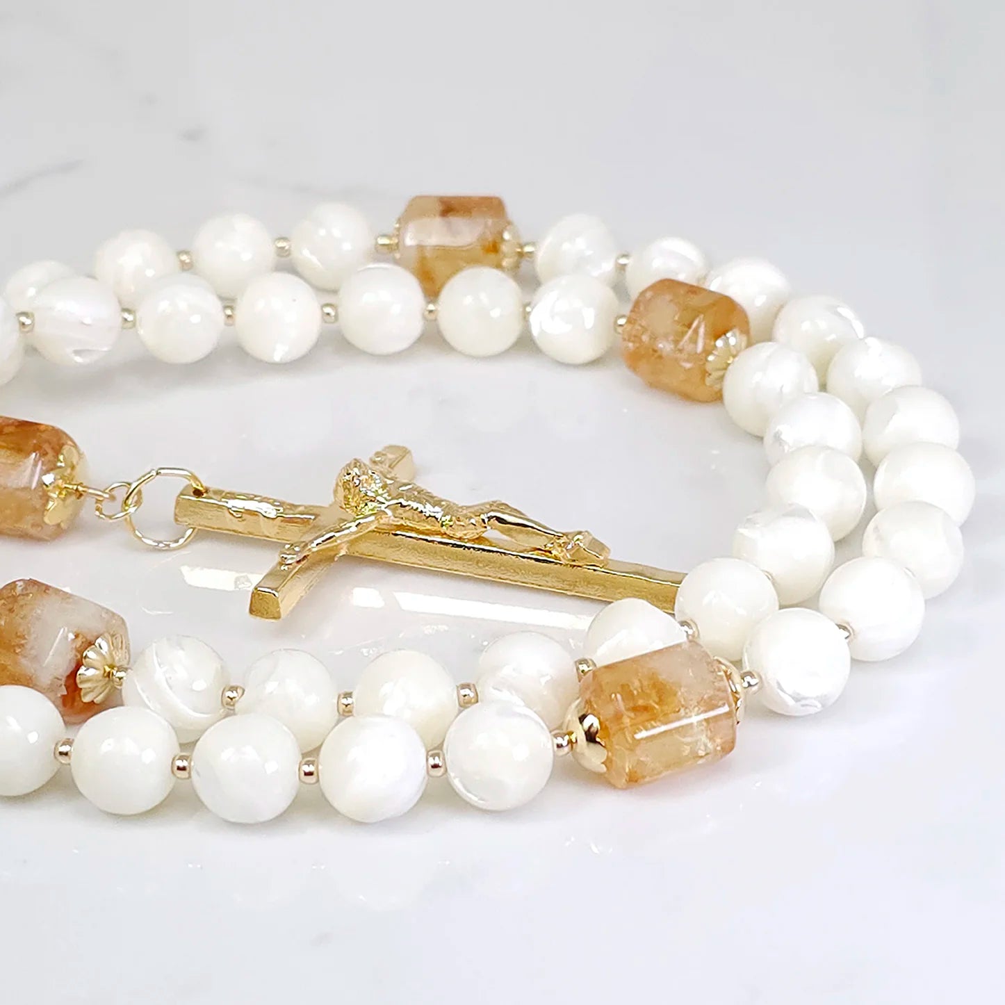 Authentic rosary highlighting the beauty of Mother of Pearl and Golden Citrine, carefully positioned on a white table.