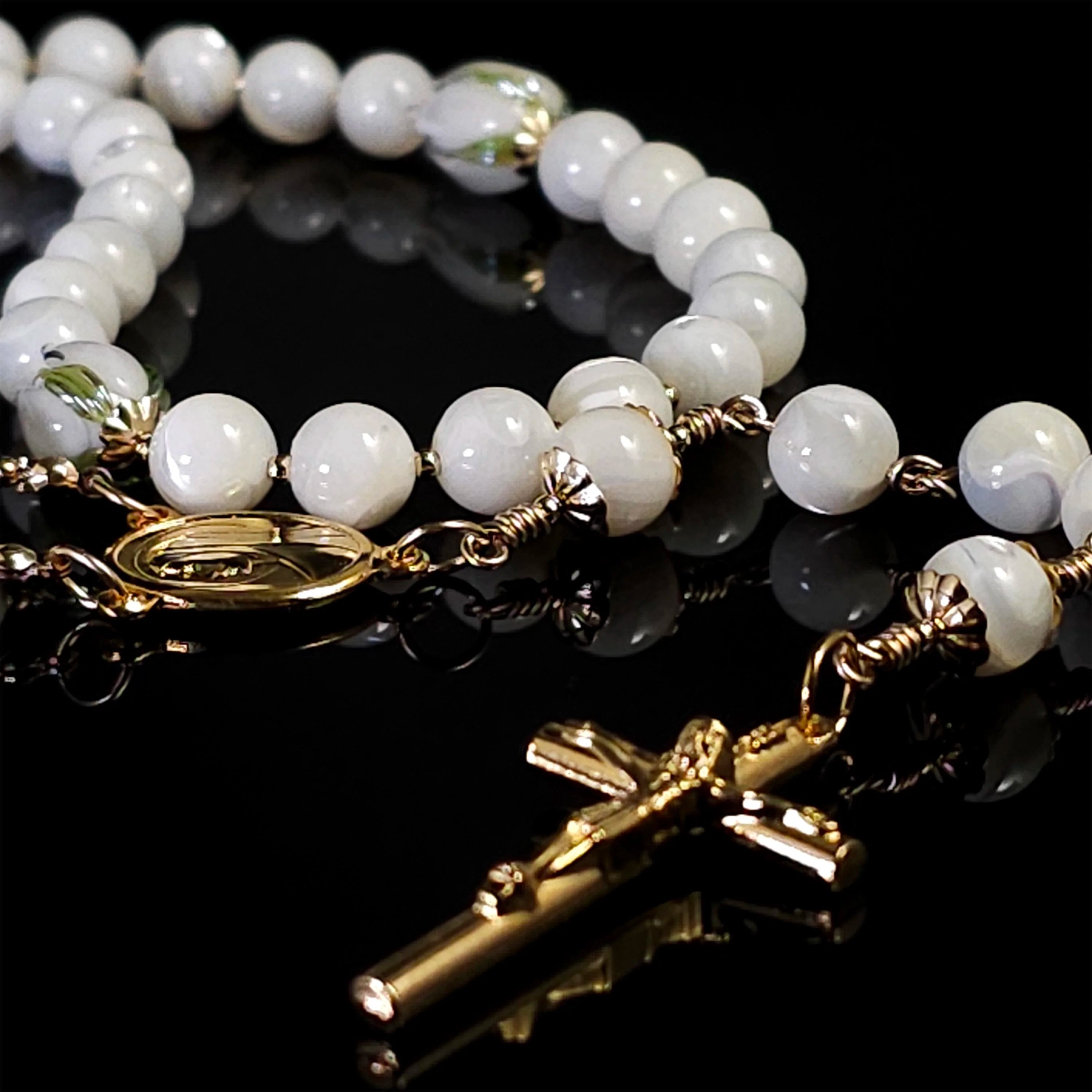 White mother of pearl tulip rosary on top of a table.