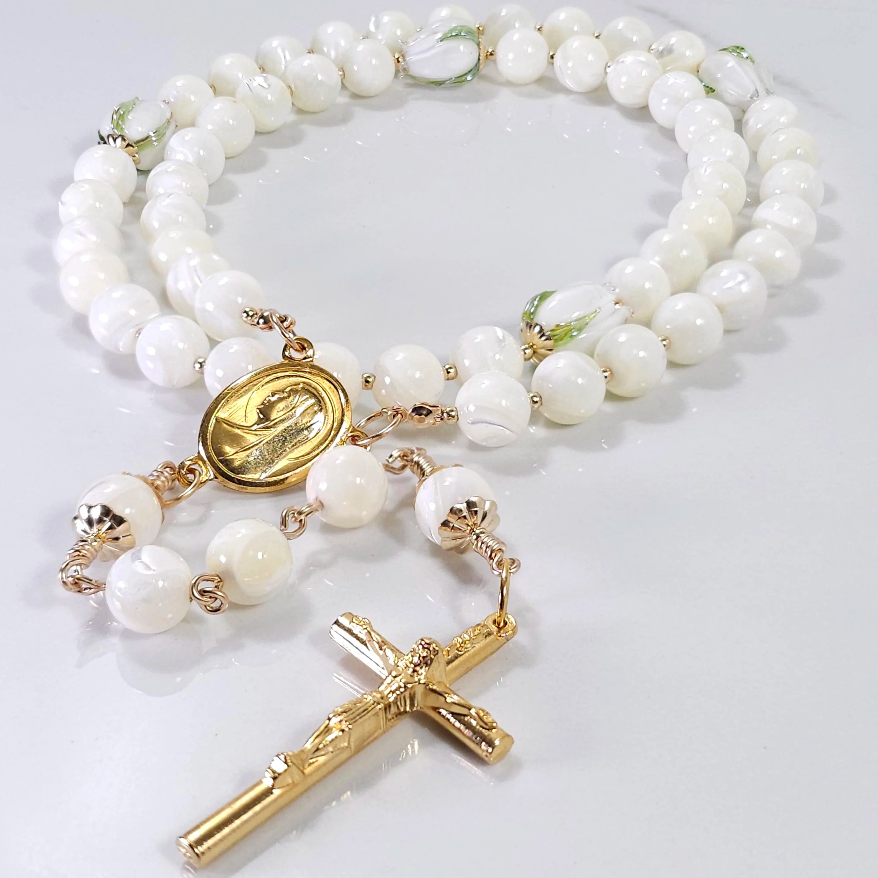 White pearl tulip rosary laying on the table.