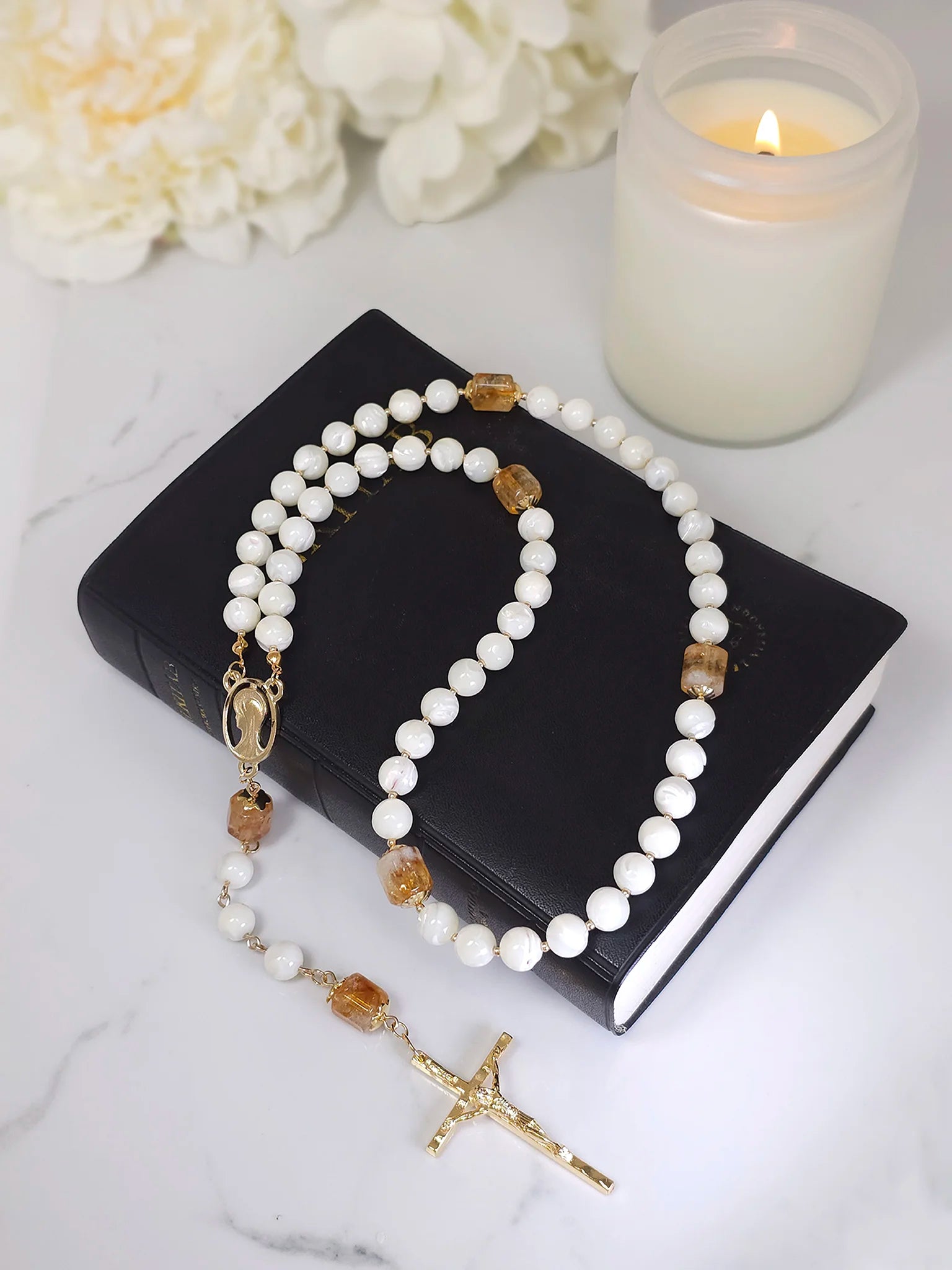 Handcrafted rosary of White Mother of Pearl and Citrine beads, with gold-filled caps, arranged on a white table.