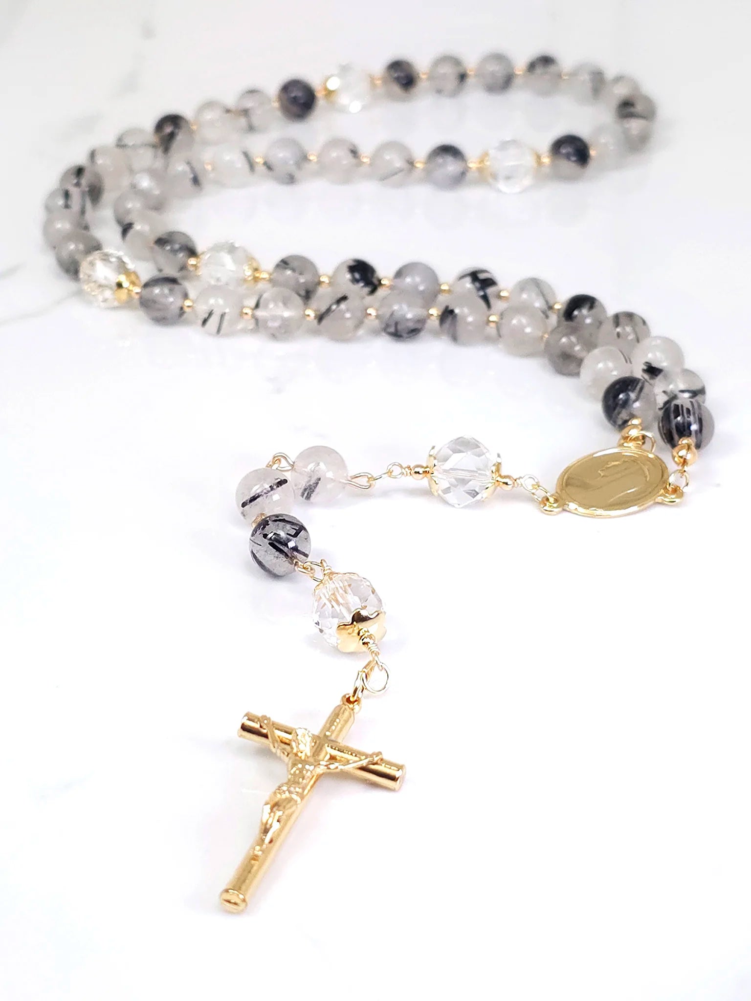 A masterful creation, accentuated by gold-filled metal findings and a Gold-plated Crucifix pendant.