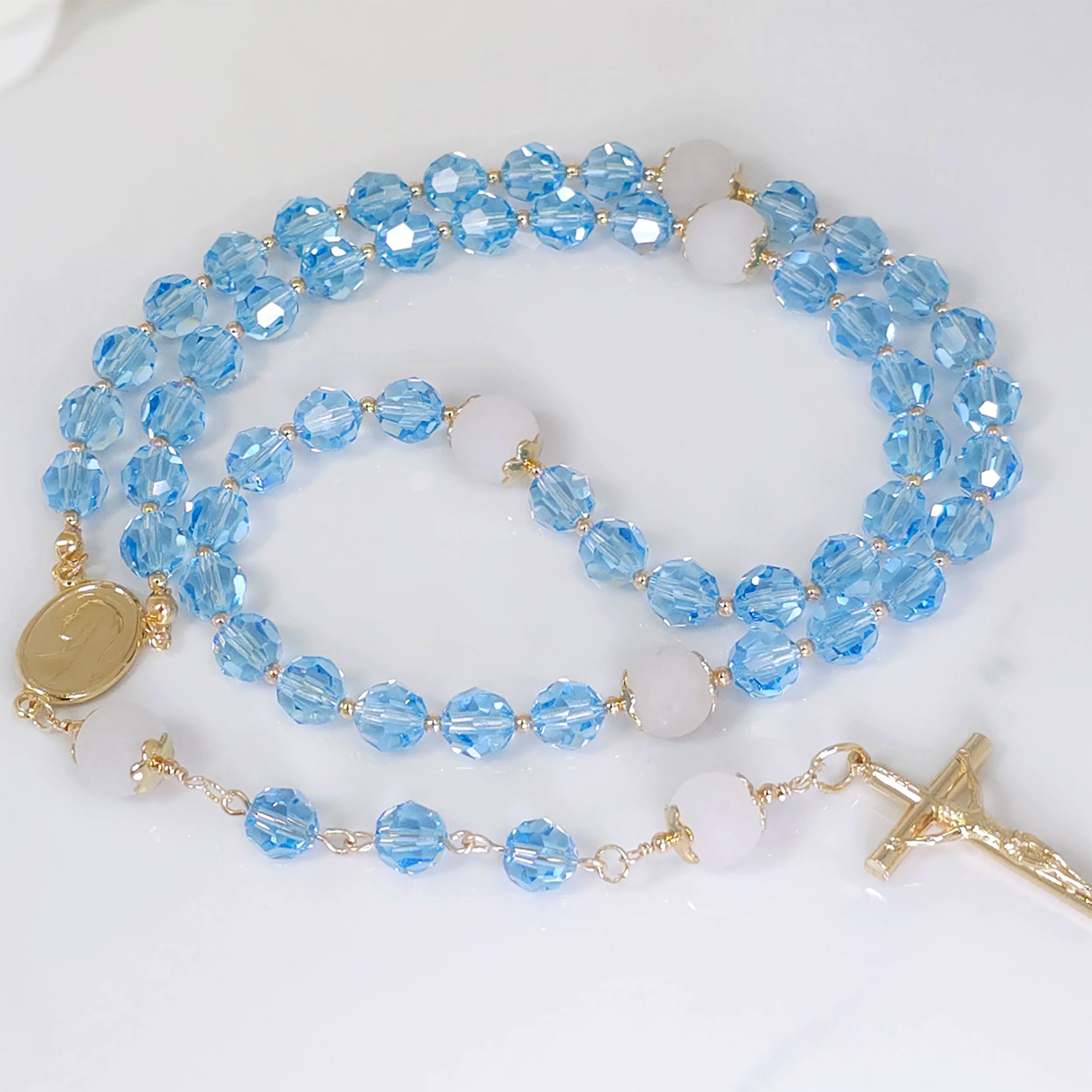 Aquamarine Austrian Crystal Rosary Necklace with 8 mm Blue Aquamarine beads, gracefully displayed on a table.