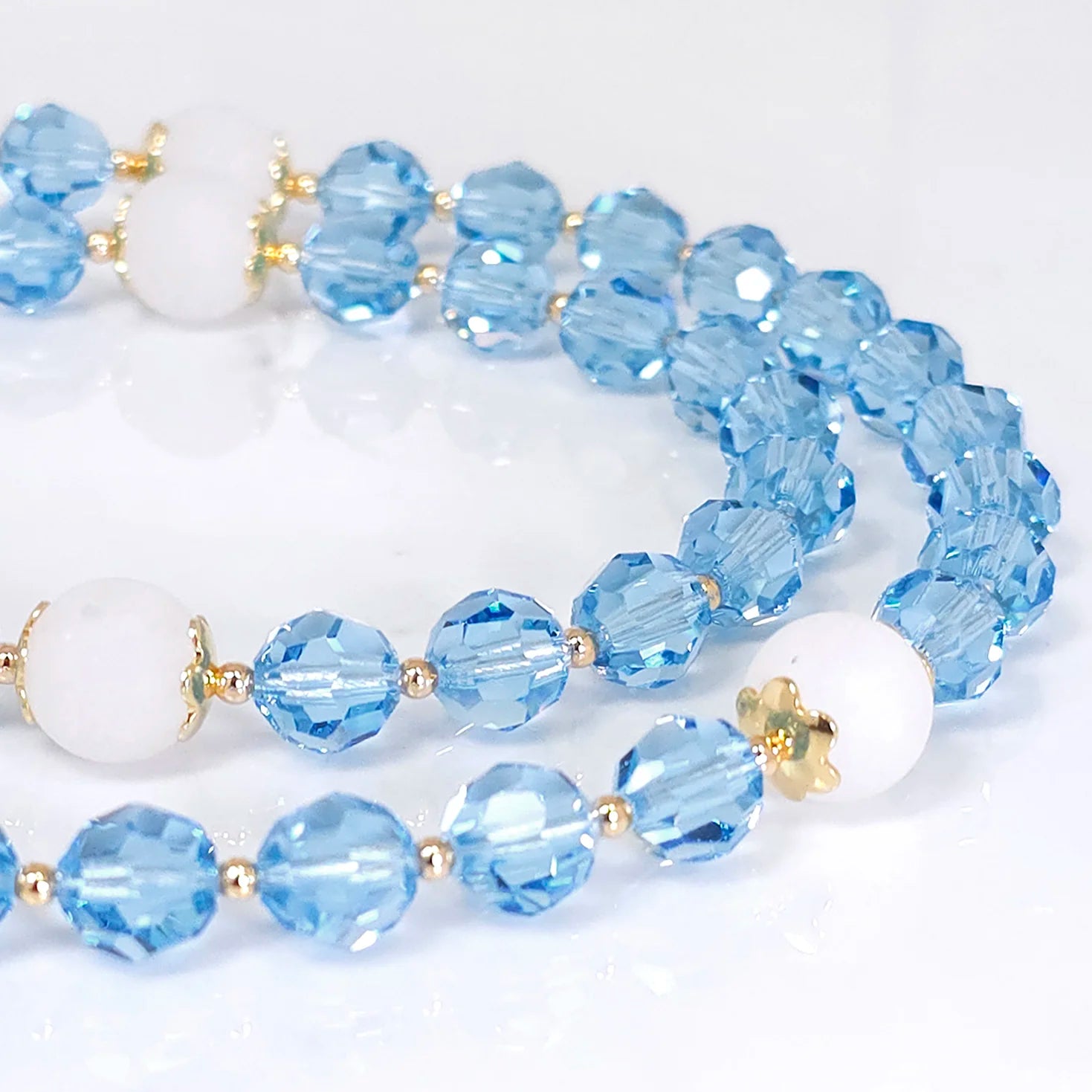 Elegant rosary made with blue Swarovski beads, accentuated by 10 mm Matte White Jade.