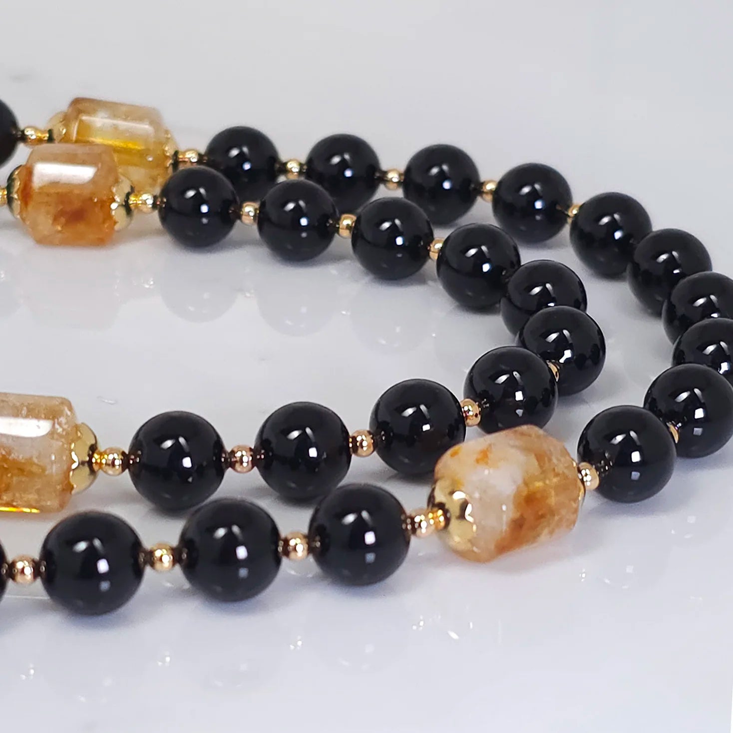 Black Rosary blending the Onyx with the Golden Citrine, with gold-filled wire on a white table.