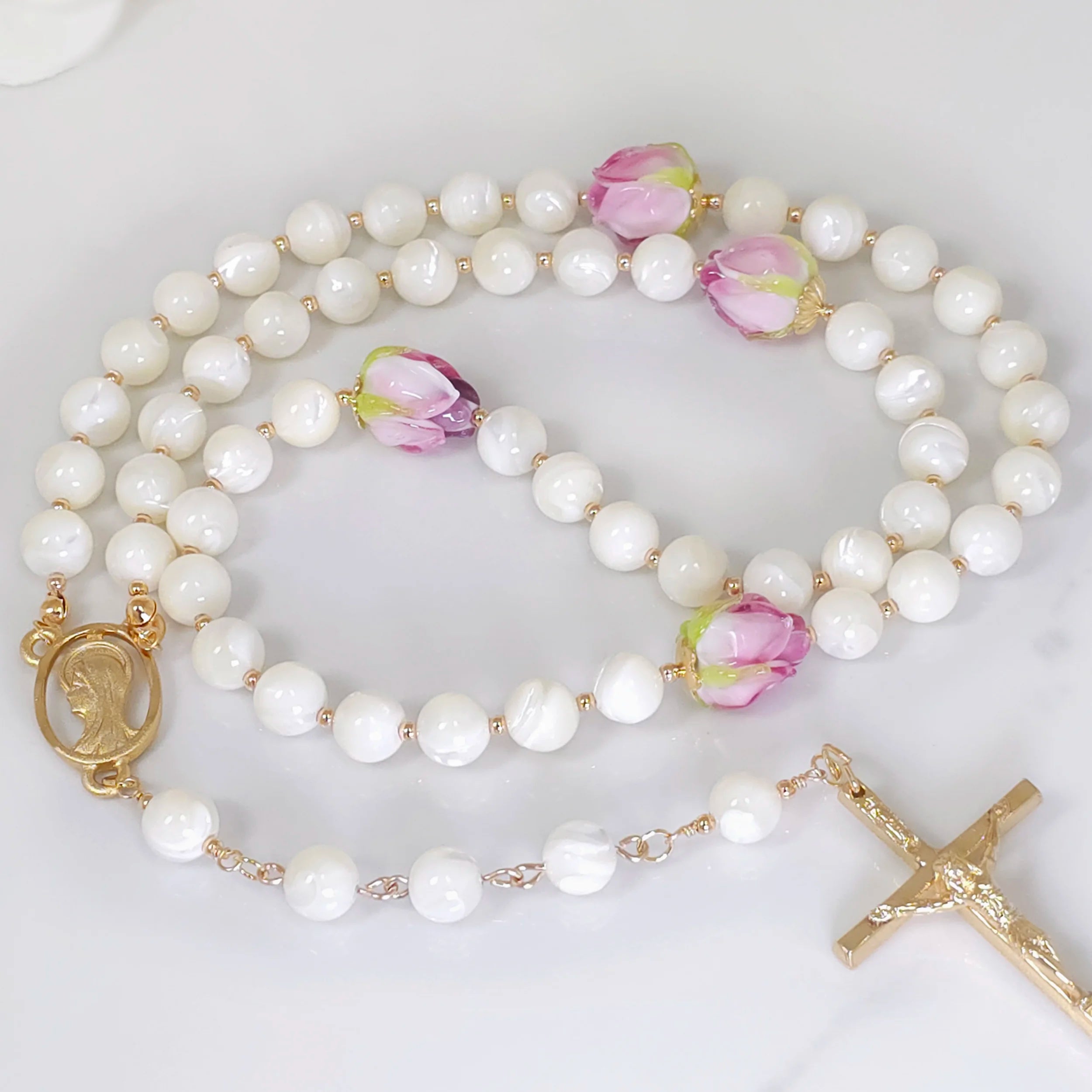 White Mother of Pearl Rose Flower Rosary necklace, gracefully laid out with distinctive beads.