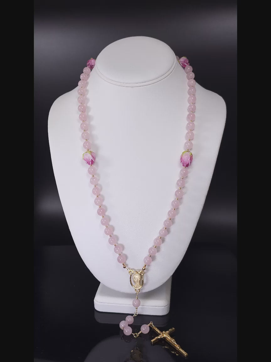 Necklace rosary made of Pink Rose Quartz and intricate rosebud lamp-work beads, elegantly positioned on a white table.