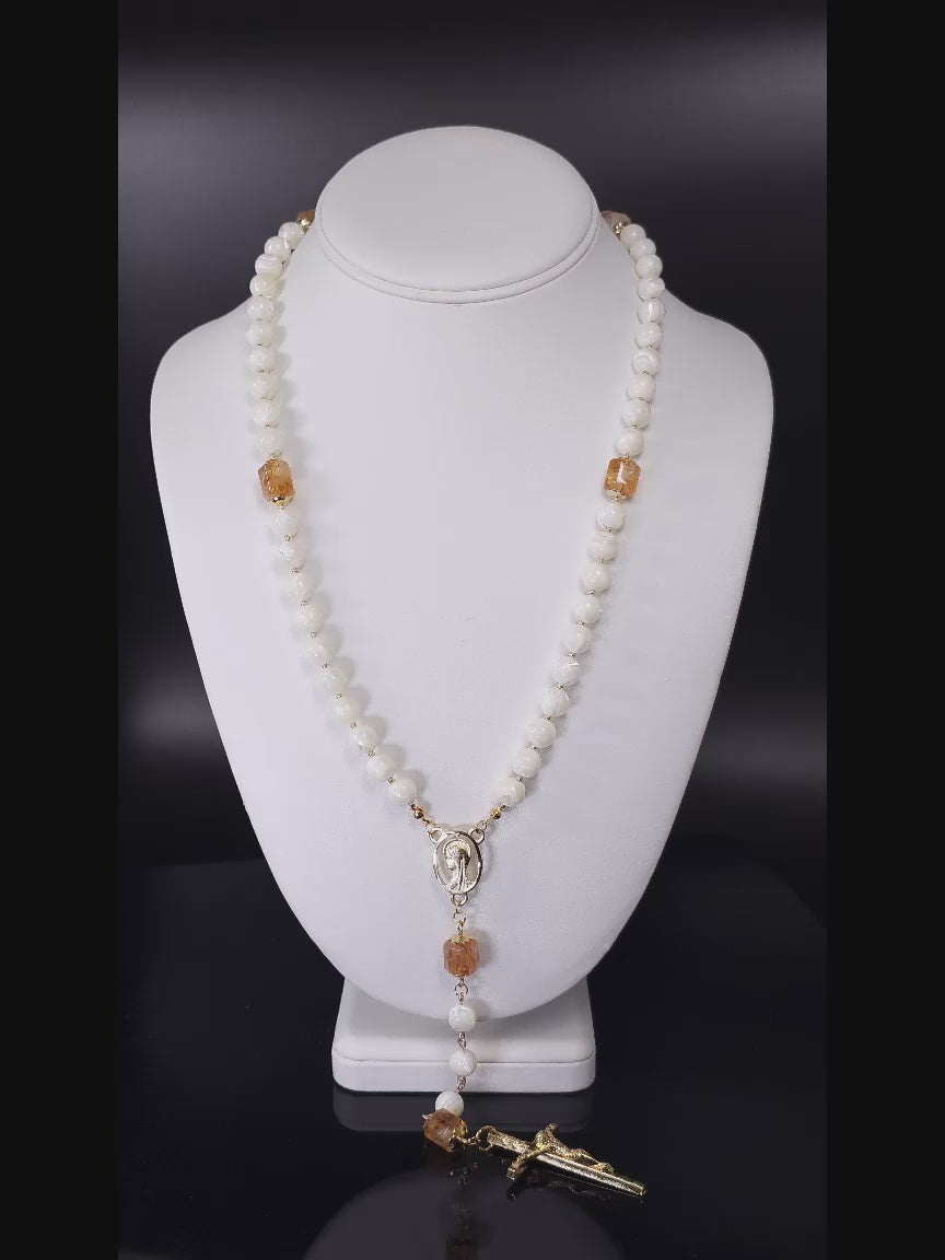 Traditional Catholic rosary with Mother of Pearl, golden Citrine, and gold-filled findings, showcased on a white table.
