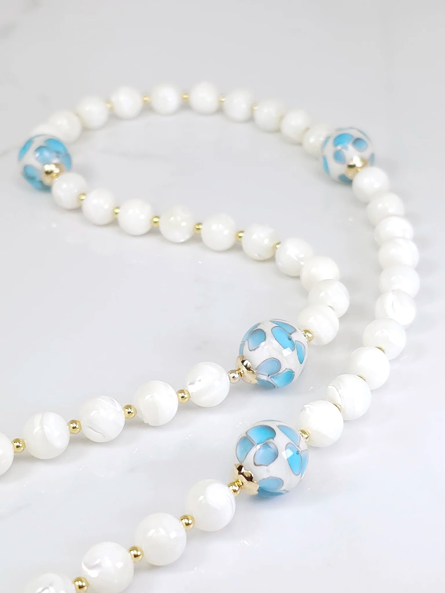 Authentic rosary beads made of White Mother of Pearl, gracefully laid out on a table.