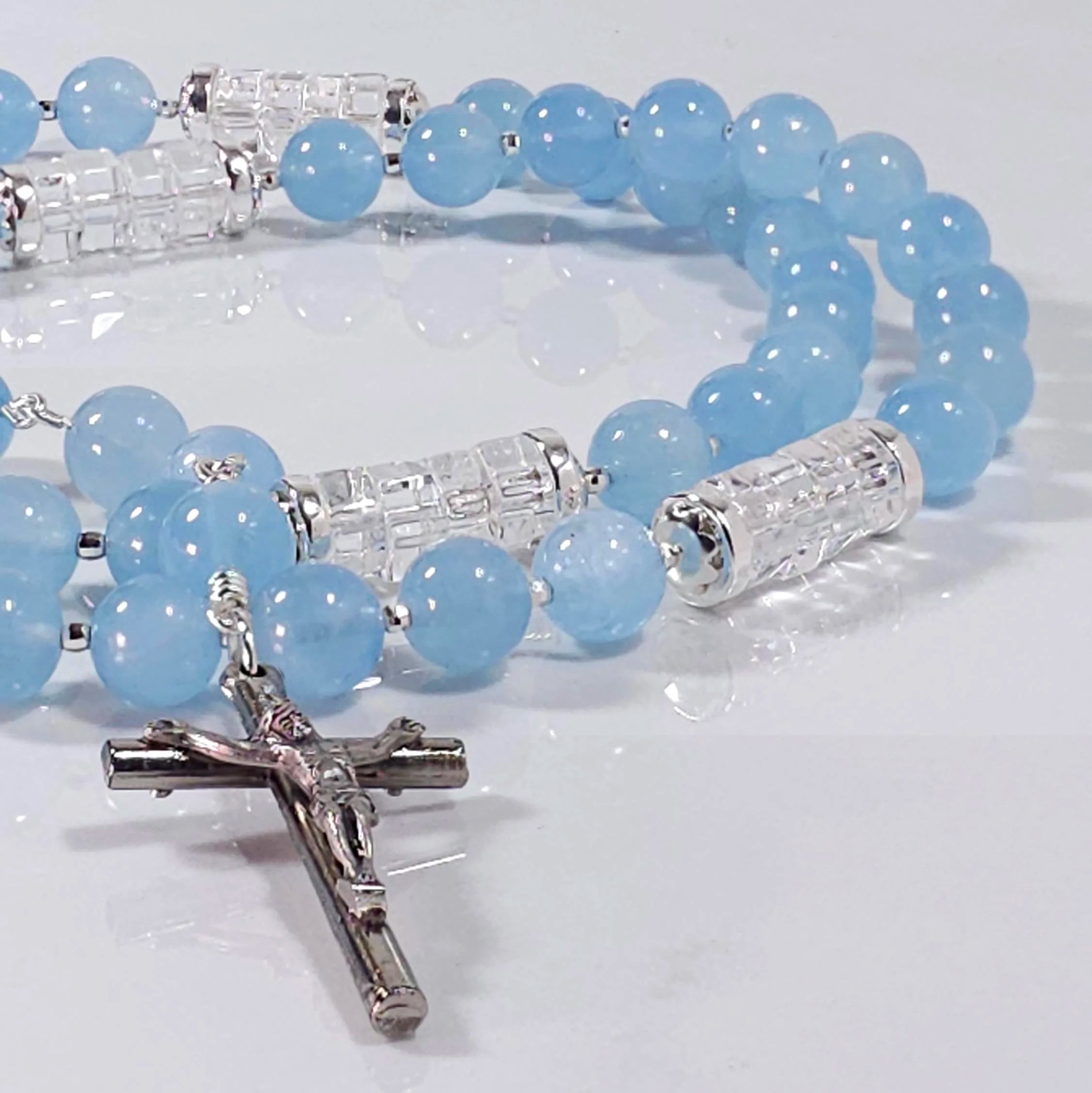 Marian blue rosary laying on white marble.